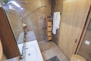 Un baño con cabina de ducha de vidrio, tocador de madera y perchero para toallas.