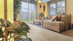 A living room with a sofa, coffee table, and potted plants. - Nice apartment near the center (Martigny)