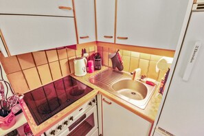 A compact kitchen with a gas stove, oven, and sink. There is a small countertop with a kettle and a toaster. - Excellent apartment with free covered parking (Lens)