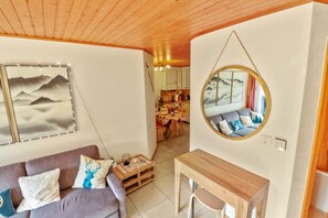 A cozy living room with a wooden ceiling, a sofa with cushions, a small wooden table, and a wall-mounted mirror. - Excellent apartment with free covered parking (Lens)