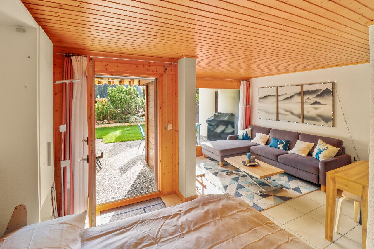 Um quarto aconchegante com teto de madeira, um sofá, uma mesa de centro e uma cama.