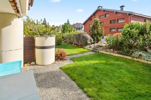 A well-maintained garden with a lawn, a large rock, and a variety of shrubs and trees. - Excellent apartment with free covered parking (Lens)
