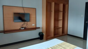 Une chambre à coucher avec un lit, un téléviseur fixé au mur et une armoire en bois.