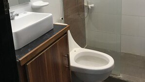 Une salle de bain avec un lavabo blanc, un miroir et des toilettes.