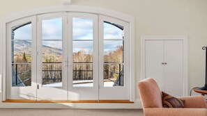 A room with a large arched window offering a view of a mountainous landscape.