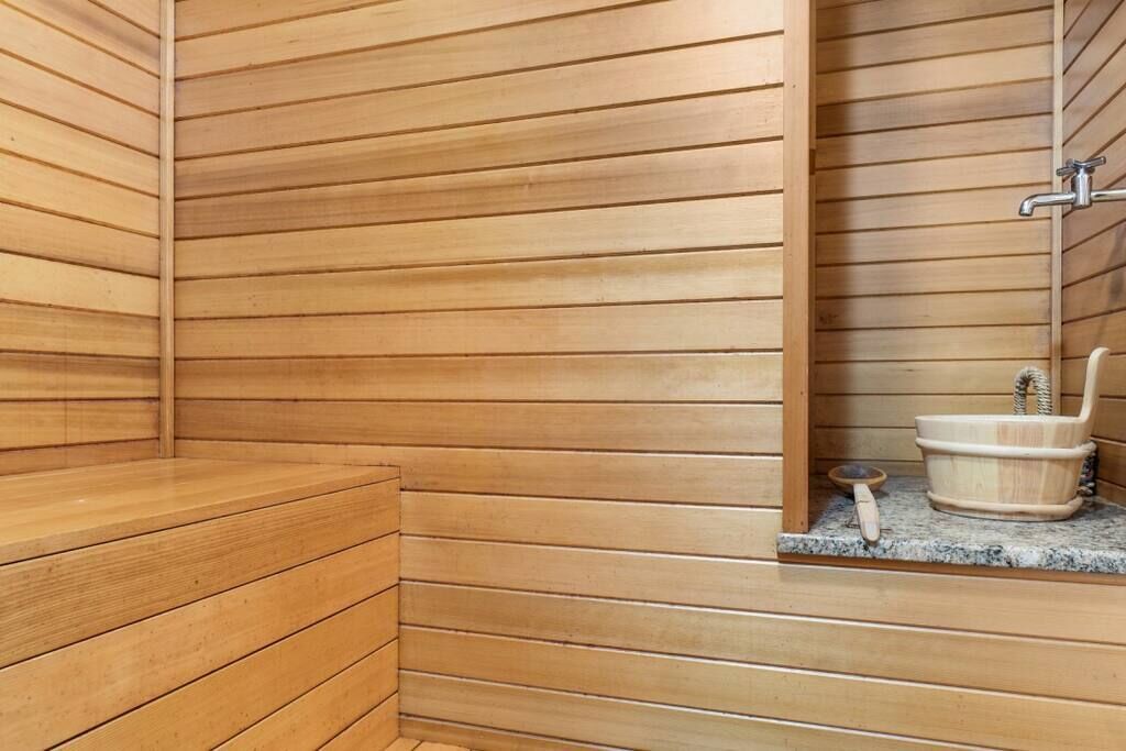 Un sauna en bois avec un banc et un petit récipient en bois contenant une brosse pour les pieds.