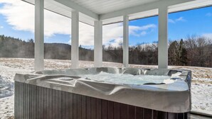 A hot tub in a covered outdoor area with a view of a snowy landscape and trees. - Private Mountain Estate | 7 Min to Okemo (Ludlow)