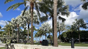 A sign for Pompano Beach with palm trees and a clear sky in the background.