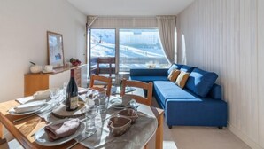 Un salon moderne avec un coin repas, un canapé bleu et une table dressée pour deux personnes.