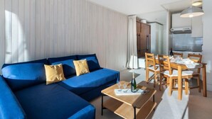 Un salon moderne avec un canapé bleu, une table à manger en bois et des chaises.