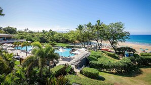Un resort con piscina, playa y abundante vegetación.
