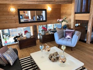 L’intérieur d’un chalet confortable, avec des murs en bois, un canapé, une table basse et un miroir.