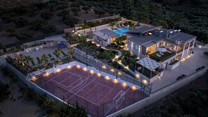 En modern bostadsfastighet med tennisbana, swimmingpool och solpaneler.