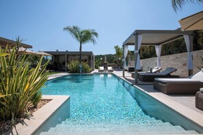 Une piscine avec des chaises longues et une pergola.