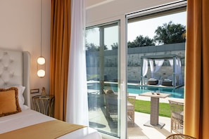 A hotel room with a bed, a glass door leading to a pool area with outdoor seating.