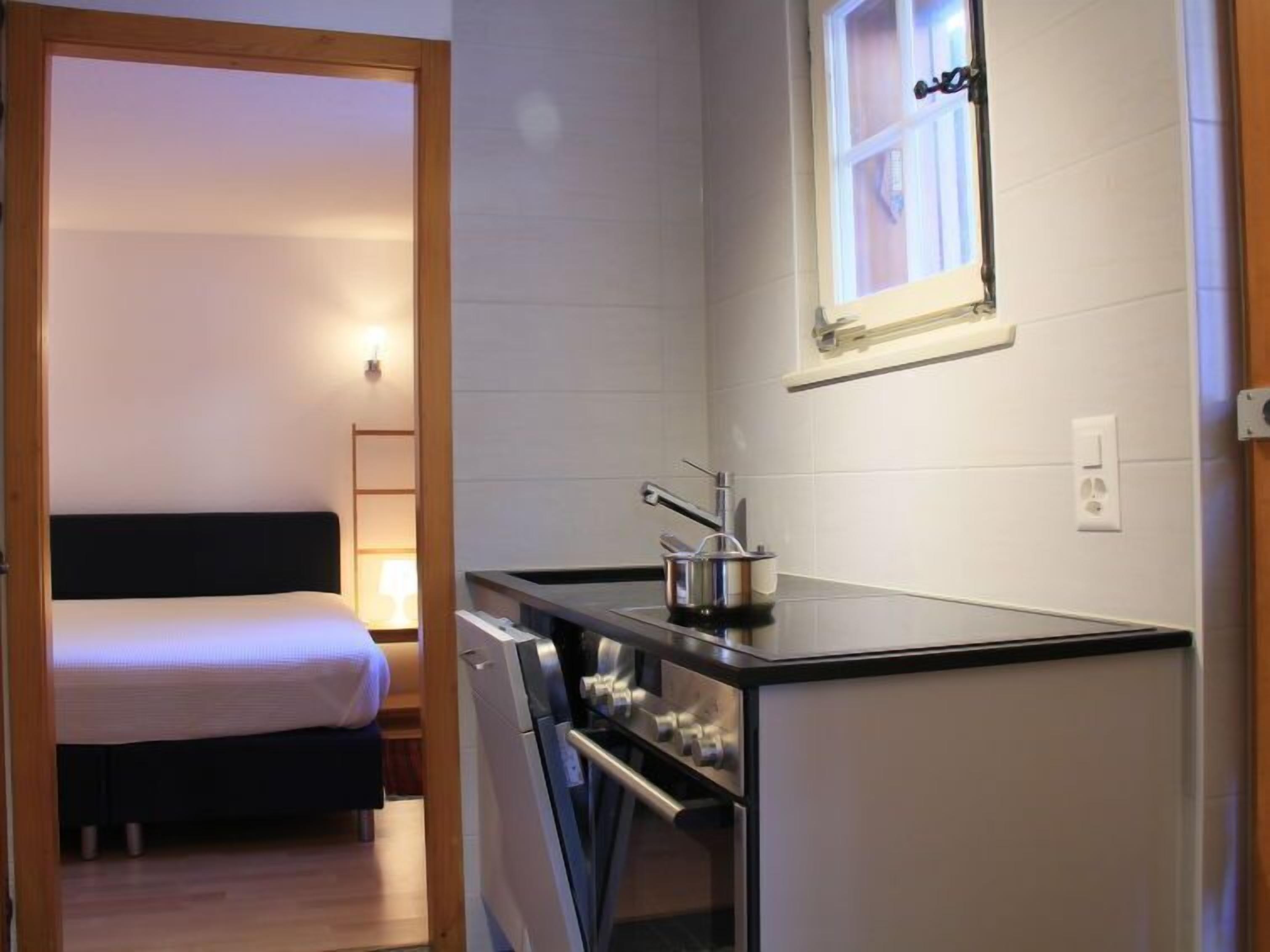 A compact hotel room with a kitchenette, a bed, and a window with a view.