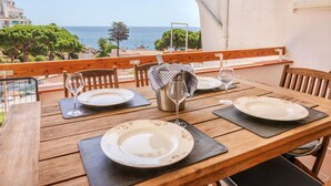 A wooden table set for dining with a view of the sea and buildings in the background.