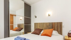 A modern bedroom with a large bed, wooden headboard, and a mirror.