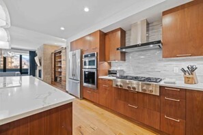 Uma cozinha moderna com armários de madeira, eletrodomésticos de aço inoxidável e bancada de mármore.