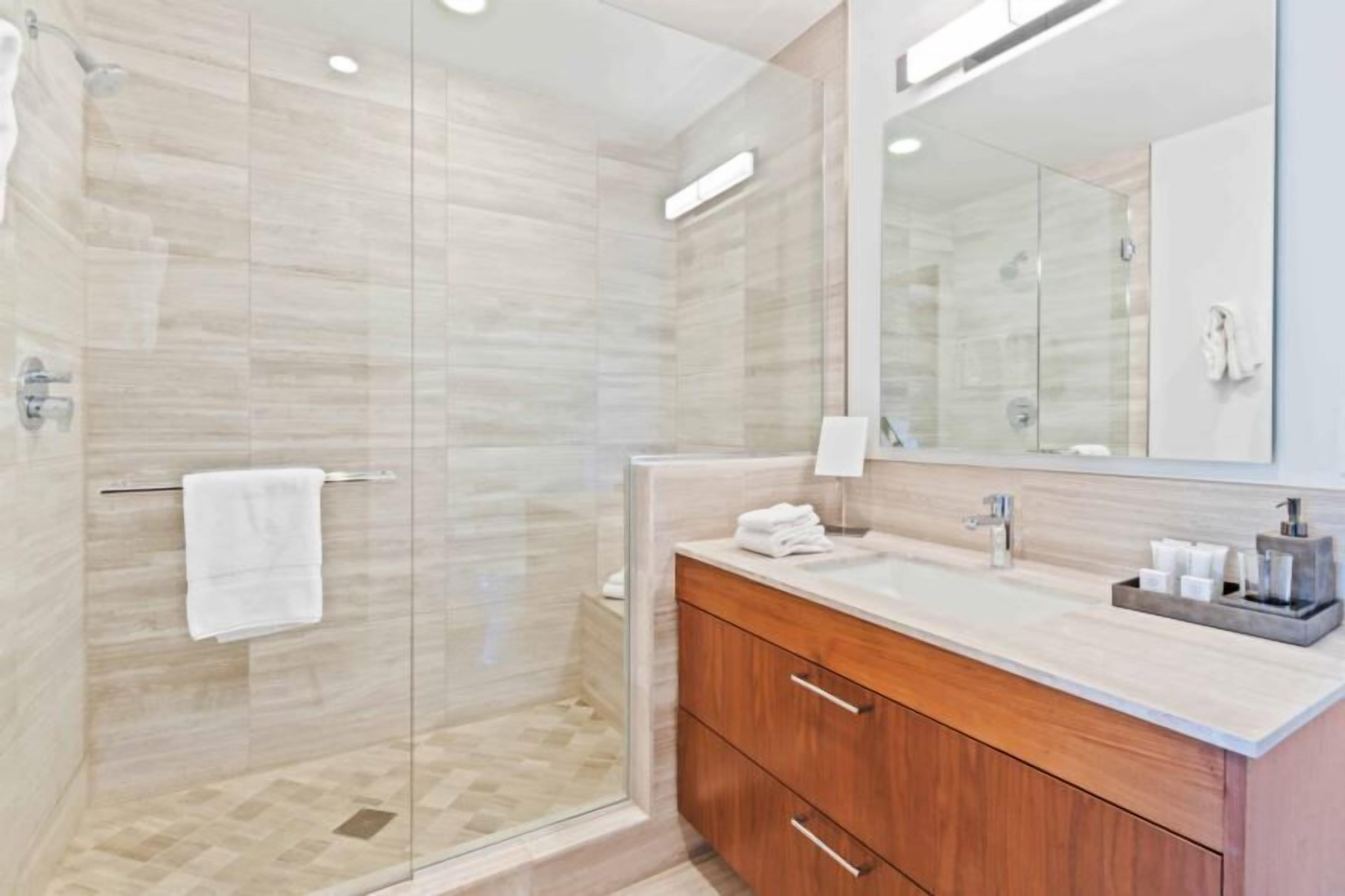 Une salle de bain moderne avec une douche à parois de verre, un meuble-lavabo en bois et un grand miroir.