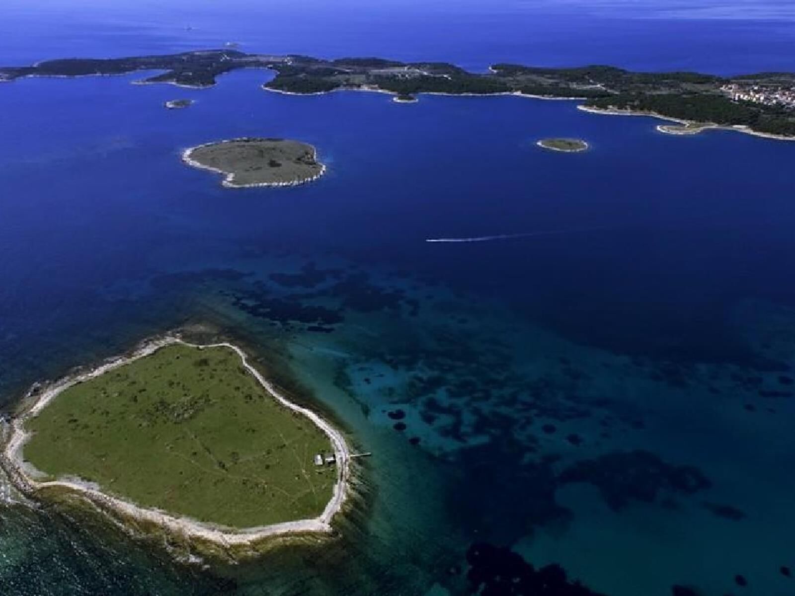 An aerial view of a coastal area with several small islands and a large central island with a distinct shape.