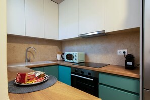 Una cocina compacta con armarios color turquesa, un microondas, un lavabo y un horno pequeño.