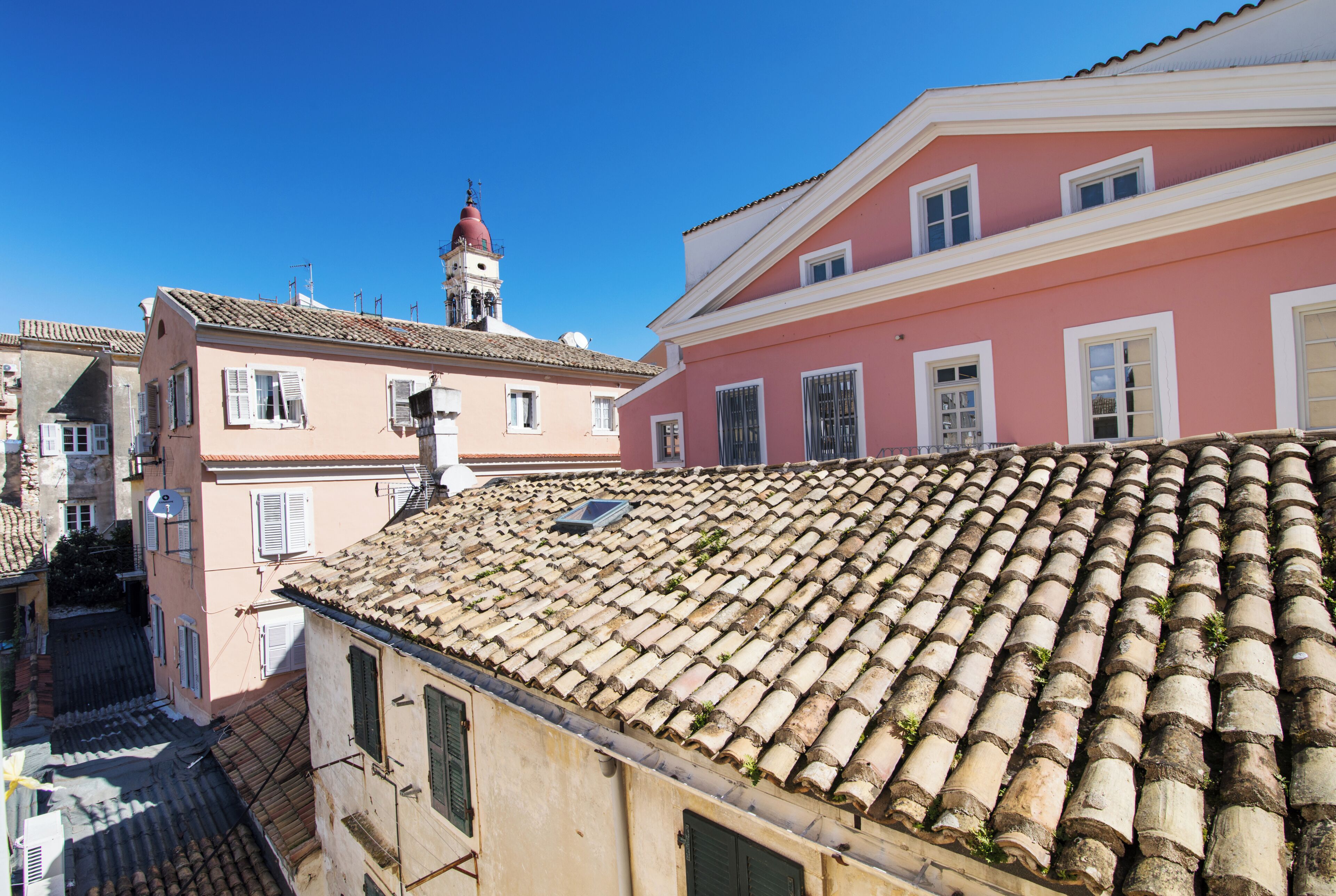 A view of a building with a tiled roof and a pink facade.