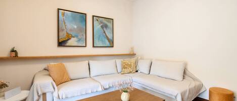A modern living room with a sectional sofa, a wooden coffee table, and two abstract paintings on the wall.