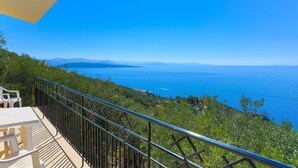 A balcony with a metal railing overlooking a coastal landscape with a clear sky. - Vista Mare Ilios in Nisaki (Corfu)
