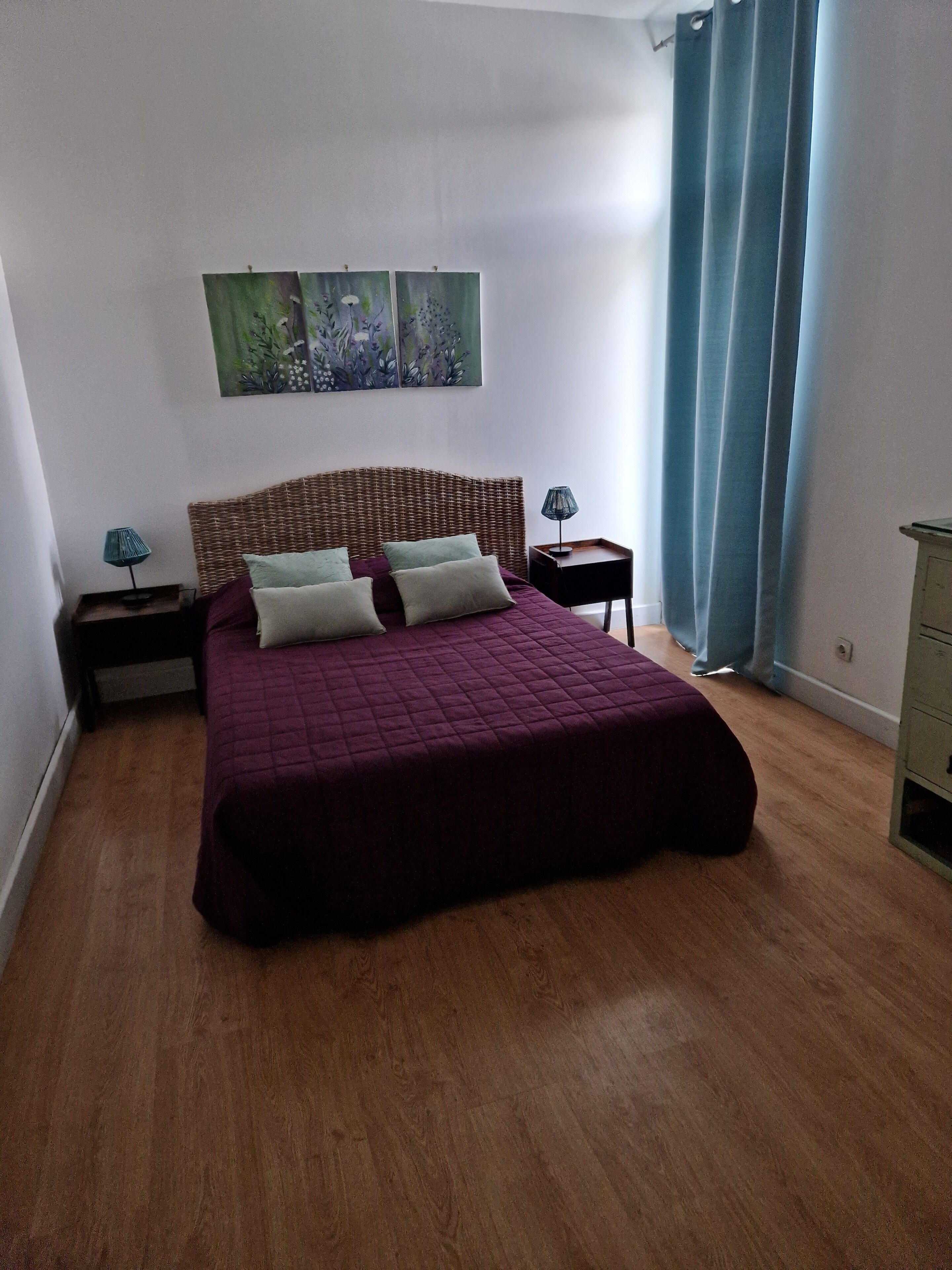 A bedroom with a large bed, two nightstands, a dresser, and a painting on the wall.