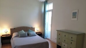 Een slaapkamer met een bed, twee nachtkastjes met lampen, een kast en een raam met gordijnen.
