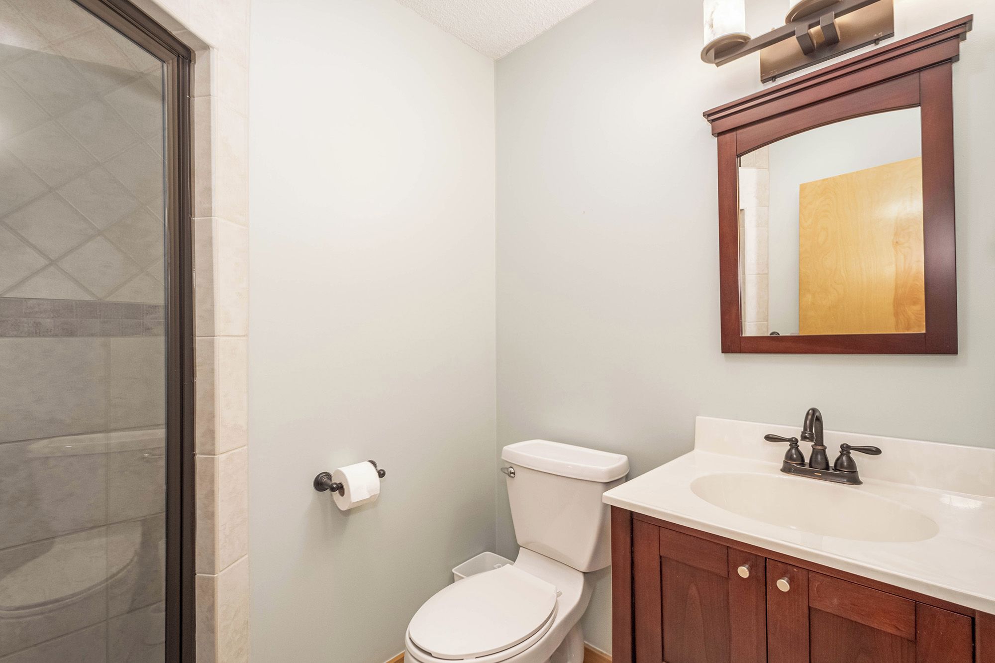 A bathroom with a toilet, sink, and mirror.