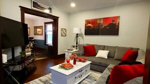 A modern living room with a grey sofa, a white coffee table, and a television. - Fischer House Indian Village Nn01 (Detroit)