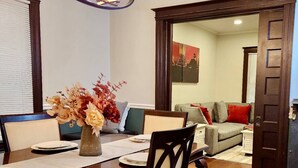 A dining area with a wooden table, chairs, a vase with flowers, and a chandelier. - Fischer House Indian Village Nn01 (Detroit)