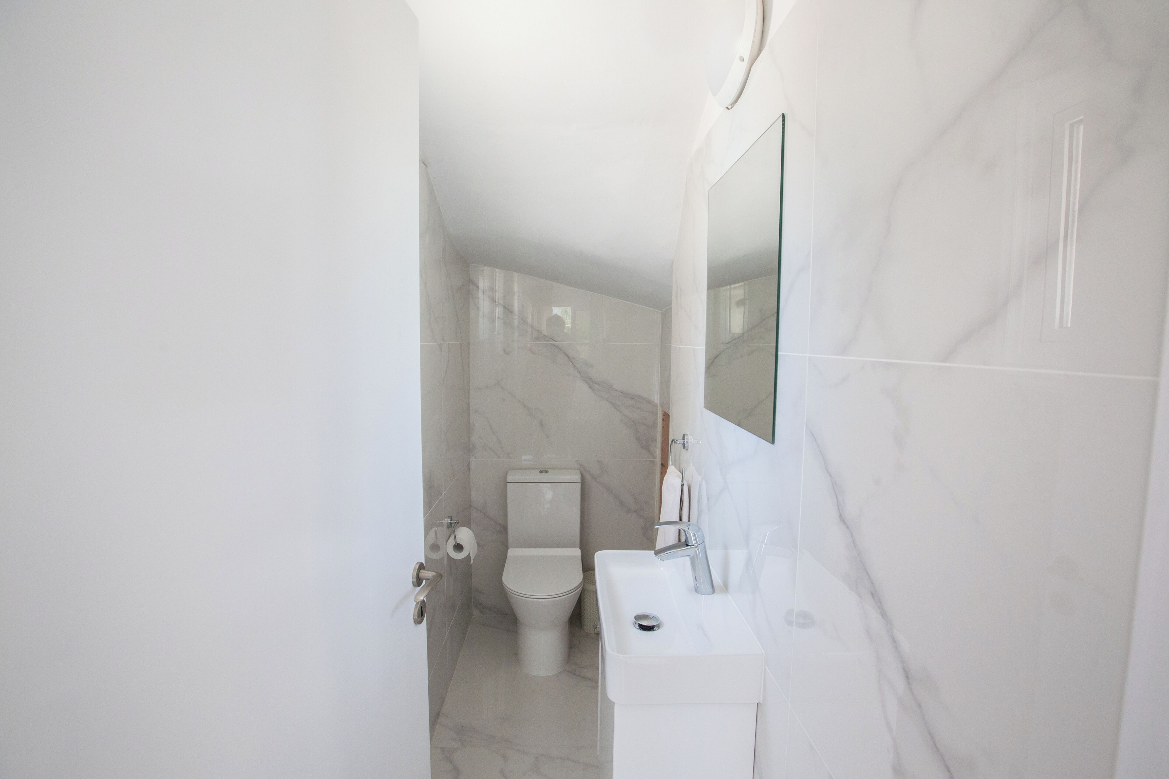 A modern bathroom with a toilet, sink, and mirror.