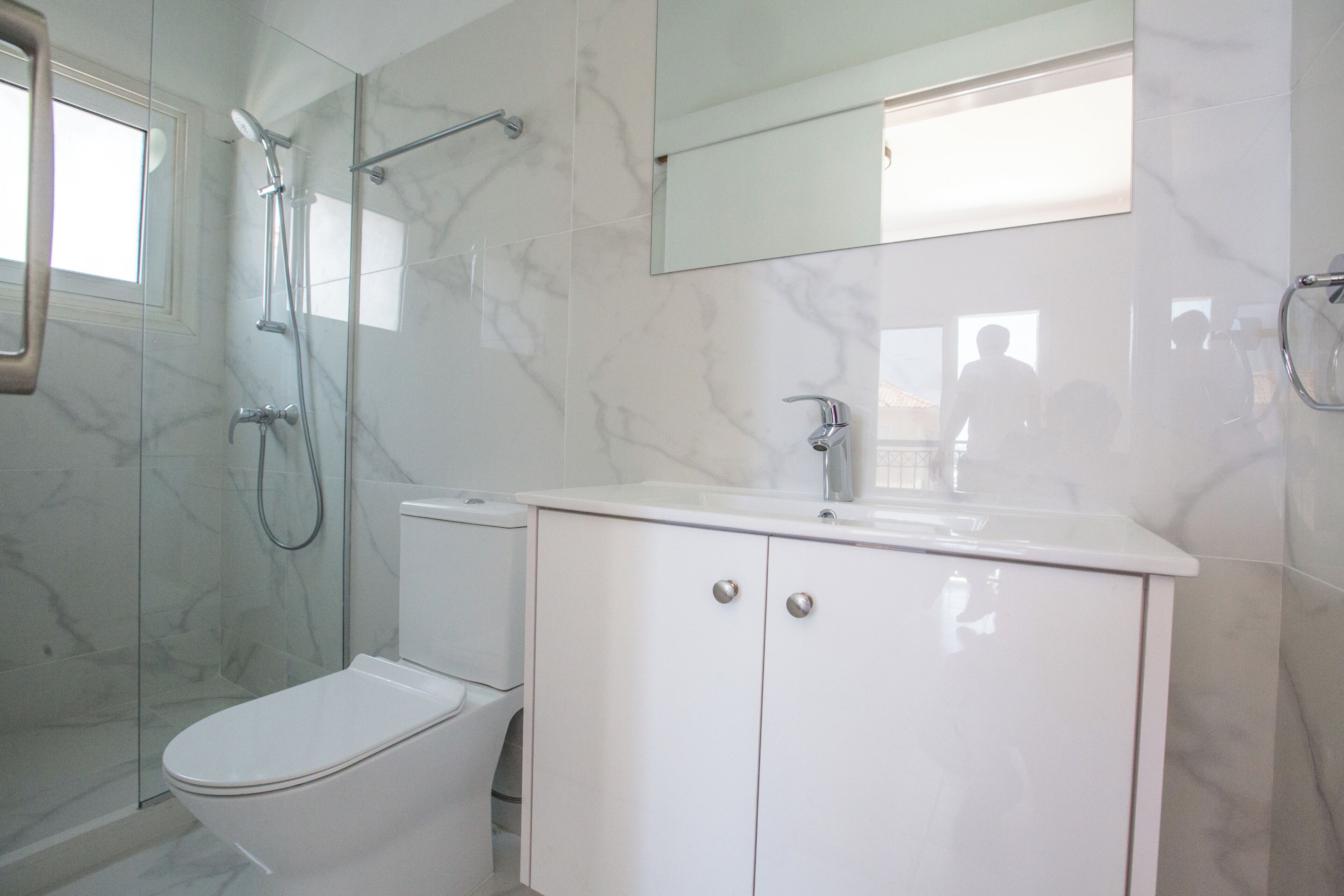 A modern bathroom with a glass-enclosed shower, a white toilet, and a vanity with a mirror.
