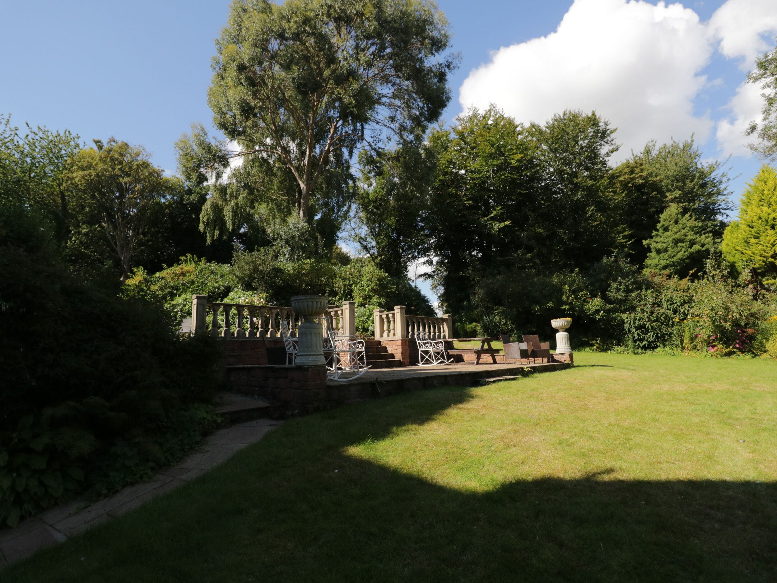 A garden with a stone bridge, seating area, and a large tree.