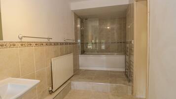 A bathroom with a bathtub, a shower, and a sink.