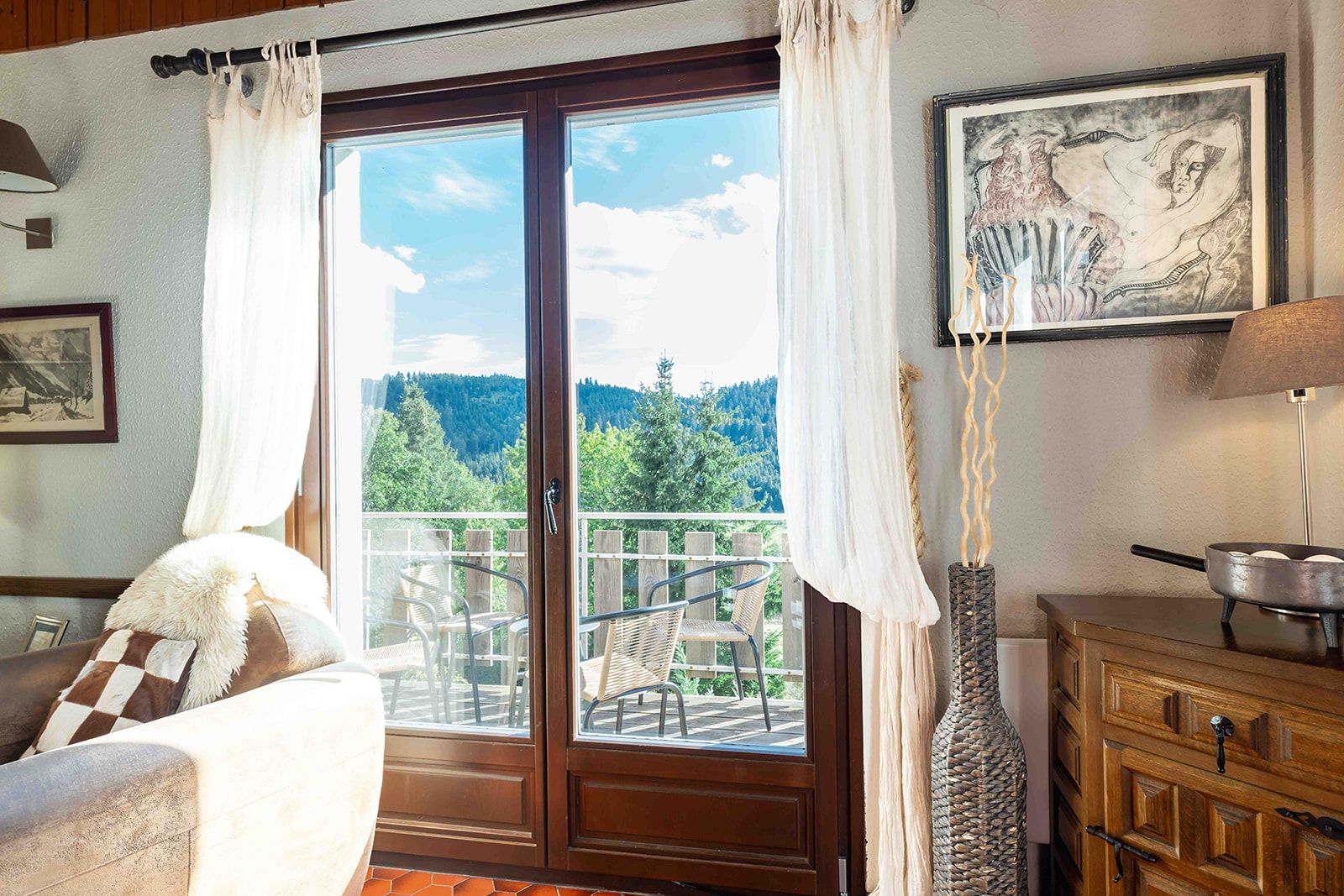 Una habitación con un aparador de madera, una silla, vistas al exterior y un cuadro en la pared.