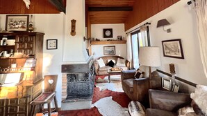 Una sala de estar acogedora con chimenea, vigas de madera y decoración rústica.