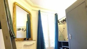 A bedroom with a wooden floor, a white dresser, a large mirror, and a wardrobe.