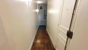 A narrow hallway with wooden flooring and white walls.