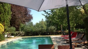 A swimming pool with lounge chairs and an umbrella.