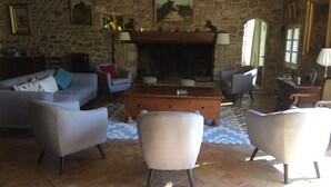 A stone-walled living room with a fireplace, sofas, and armchairs.