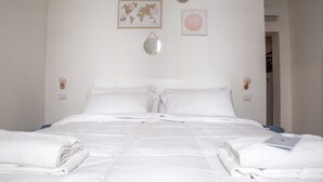 Un lit bien fait, avec du linge de lit et des serviettes blanches, une carte du monde et une affiche sur le mur avec l’inscription « Esprit serein ».