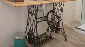 Une salle de bain avec un lavabo blanc, un miroir rond et un plan de toilette en bois.