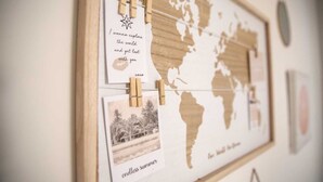 Une carte du monde sur laquelle est épinglée une photo et un petit mot écrit à la main.