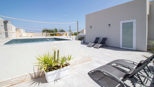 A rooftop pool area with a volleyball net, lounge chairs, and a potted plant. - Hotel Arte Mare (San Vito Lo Capo)