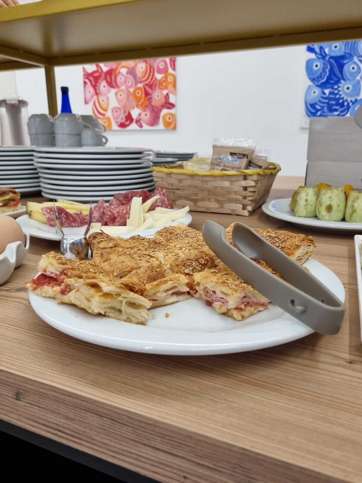 Uma mesa de buffet com diversos pratos, incluindo uma fatia de pizza, queijo e outras opções.