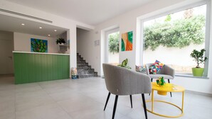 A modern interior with a green reception desk, a staircase, and a seating area with a yellow table. - Hotel Arte Mare (San Vito Lo Capo)